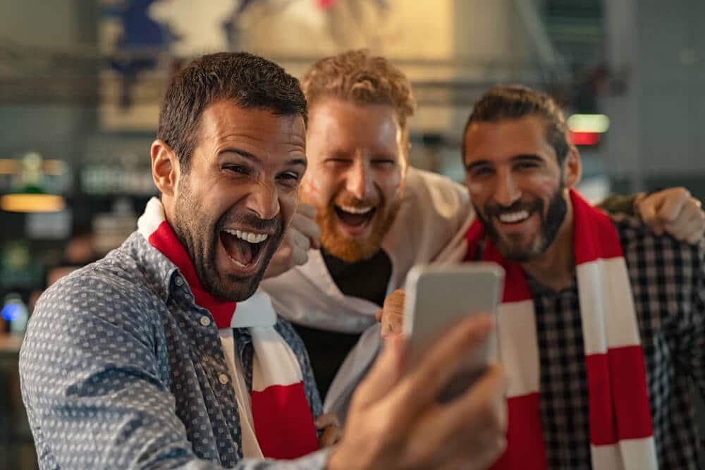 three guys laughing and looking at their smartphone