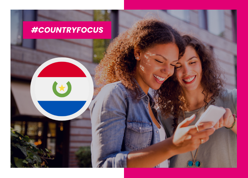 Two women look at a mobile phone with Paraguay flag on the side